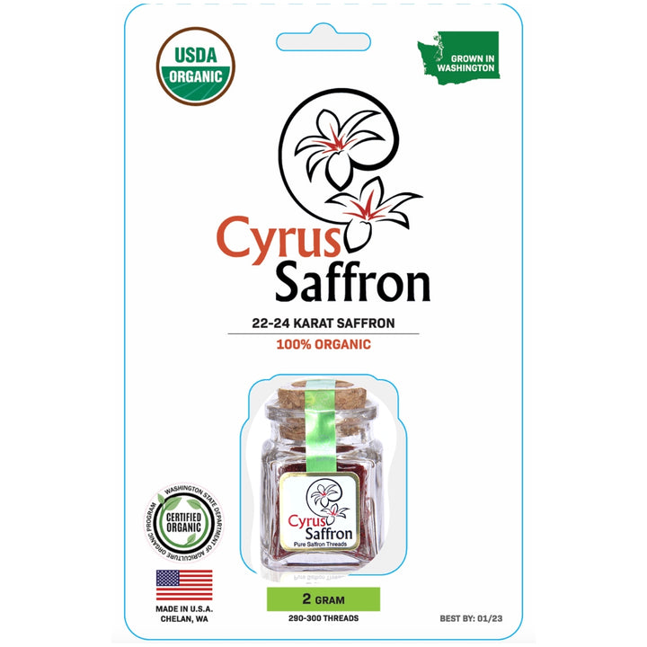Cyrus Saffron 2 grams of organic saffron in a clear glass jar with a cork stopper and yellow ribbon, presented on its retail blister card packaging with USDA Organic and Washington state grown badges.
