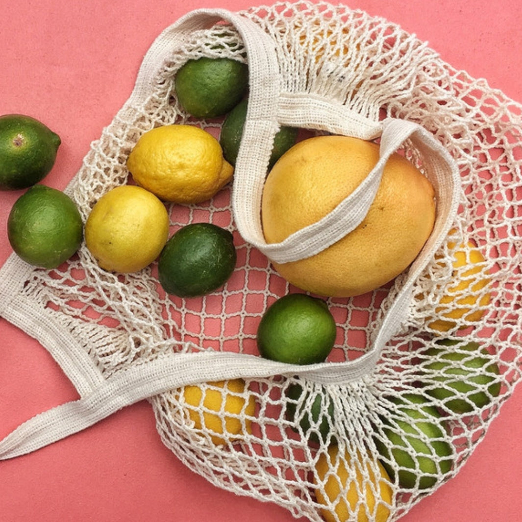 French Market Tote on a Pink Background Spilling Out Limes and Lemons | Seattle Seed Co. | Aprons & Linens @ Spice Craze®