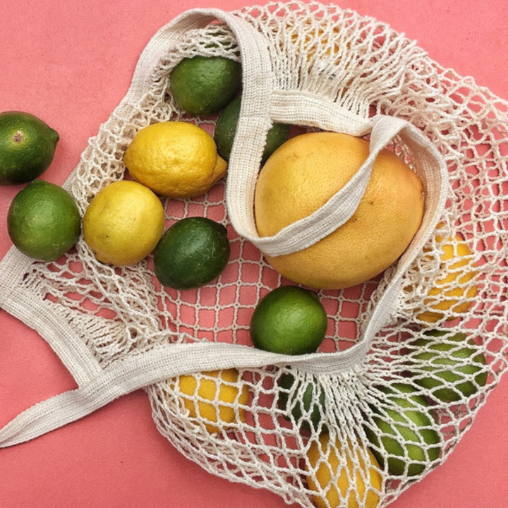 French Market Tote on a Pink Background Spilling Out Limes and Lemons | Seattle Seed Co. | Aprons & Linens @ Spice Craze®